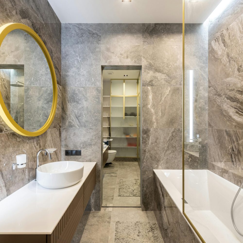 Elegant modern bathroom featuring marble walls, gold accents, and sleek fixtures for a luxurious feel.